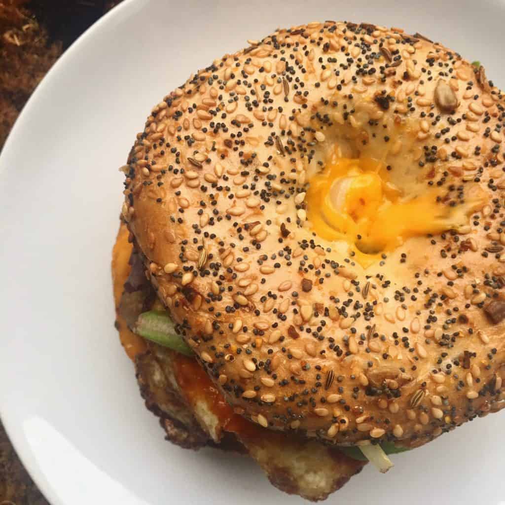 everything bagel sandwich with fried egg and hot sauce.