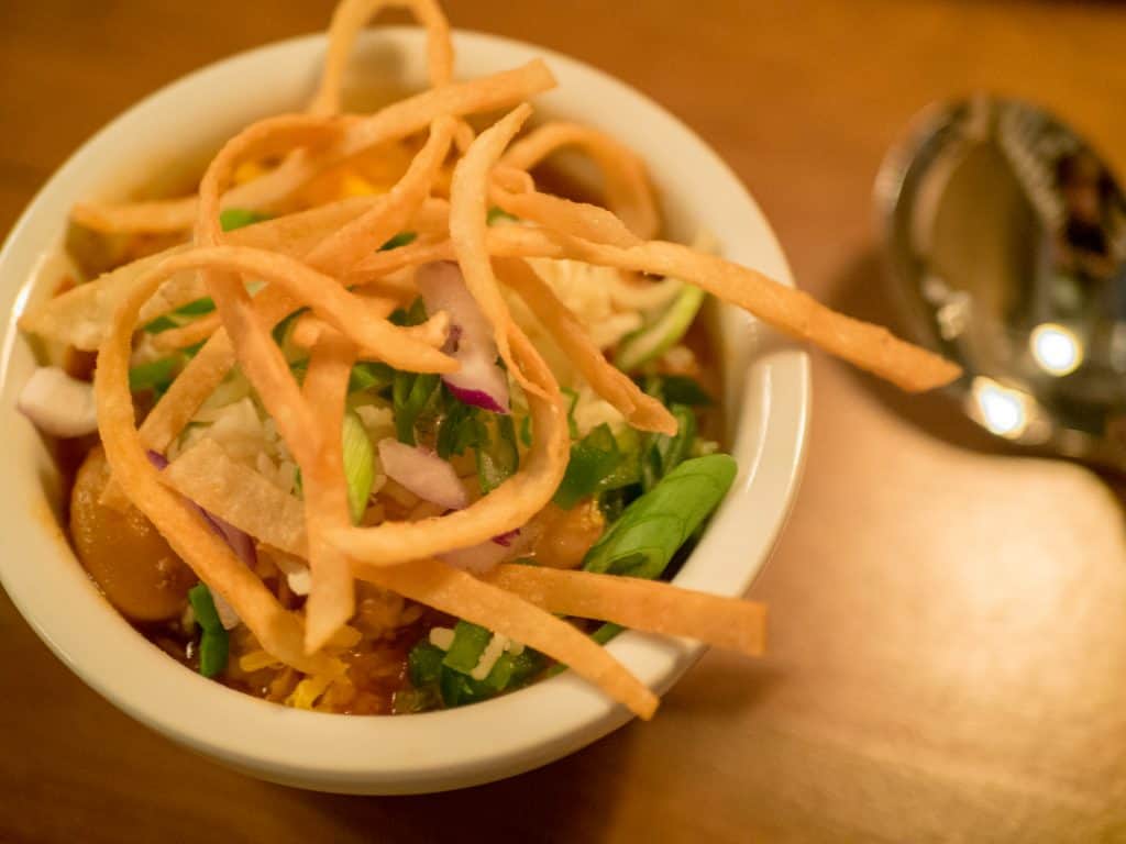 Chili topped with cheddar cheese and green onions in a bowl.