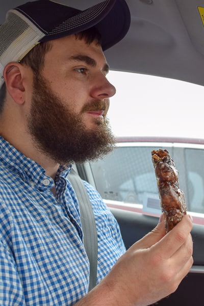 Man eating apple fritter from Kelly's Bakery Donuts & More.