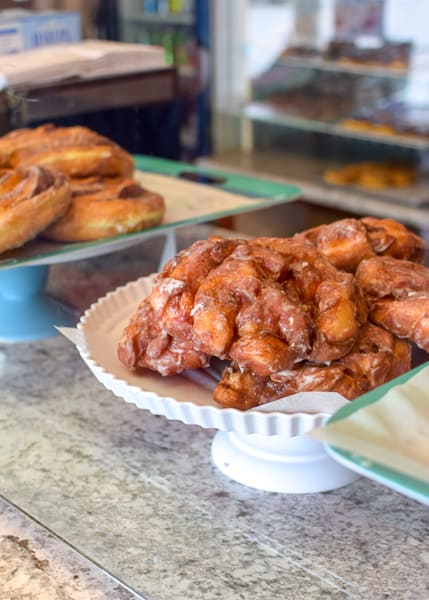 Pile of apple fritters on a white serving dish at Jupiter Coffee & Donuts.
