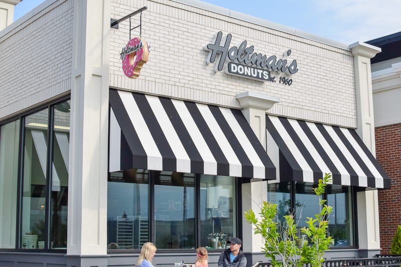 Holtman's donuts storefront and retail store with family sitting on patio.