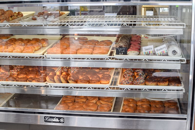 Daily donut selection in a bakery display case inside of Kelly's Bakery Donuts & More.