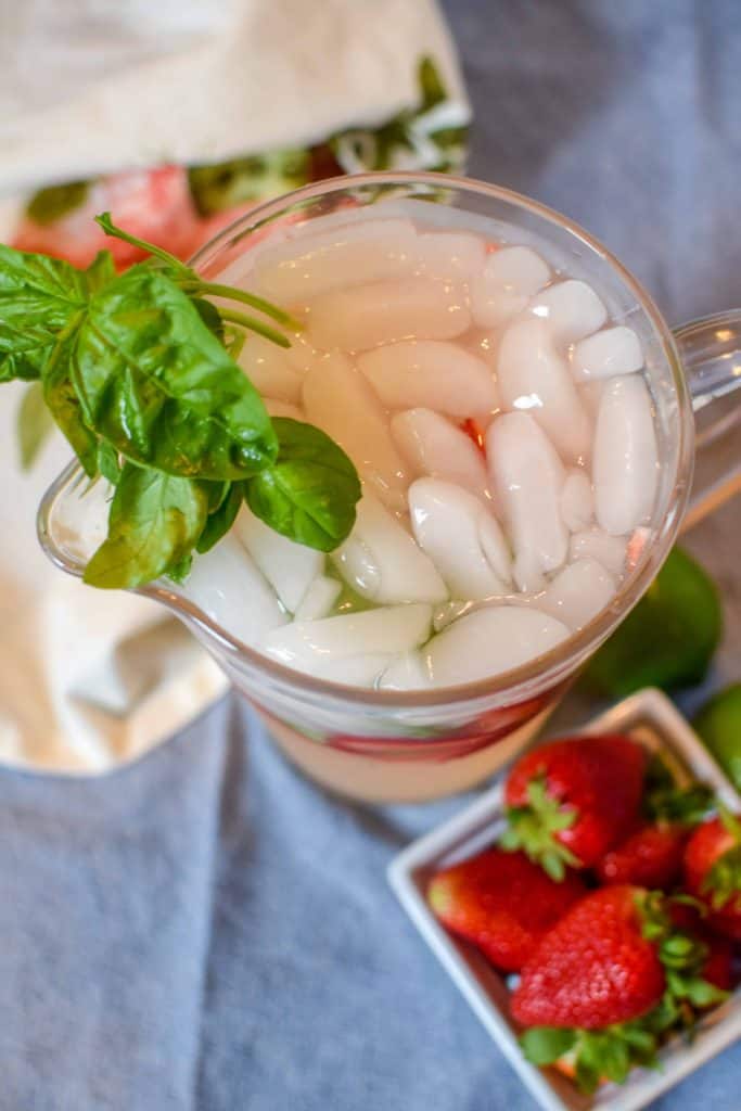 Pitcher full of Strawberry Basil Margarita garnished with fresh basil from the garden.