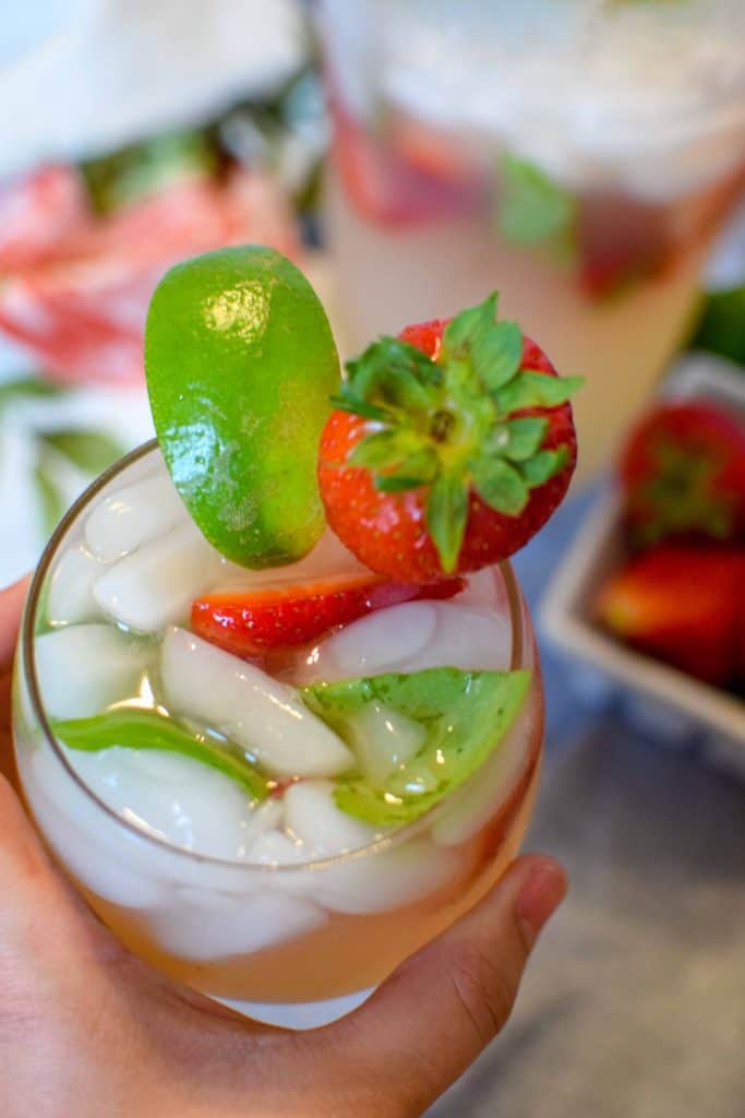 Strawberry Basil Margarita in a wine glass topped with a fresh strawberry and lime wedge.