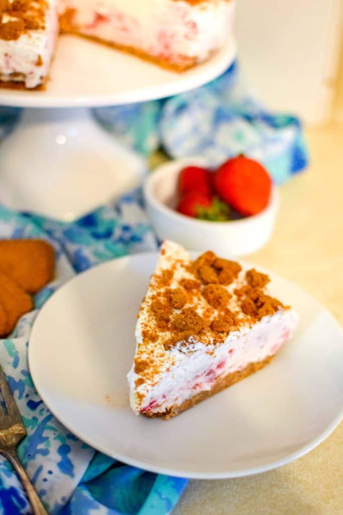 Strawberry Ice Cream Cake with Cookie Crust on a white plater with fresh strawberries in a cup.