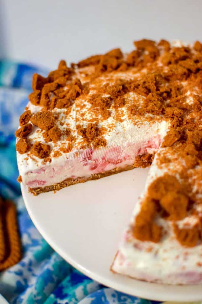 Whole Strawberry Ice Cream Cake on white cake display platter with first slice taken out.