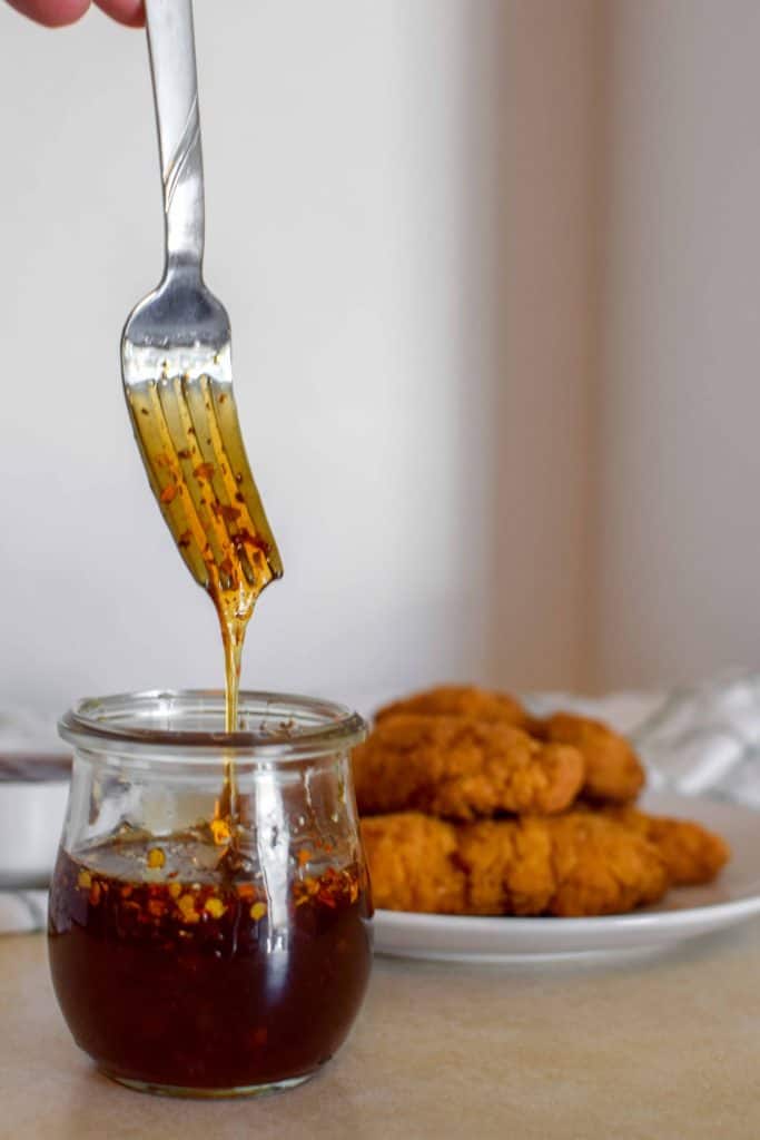 Hot honey dipping sauce being stirred by a fork.