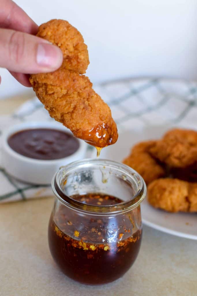 Tyson Crispy Chicken Strips being dipped in sauce.