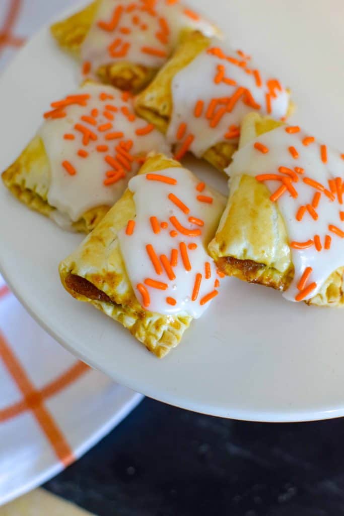 pumpkin hand pies topped with icing and sprinkles.