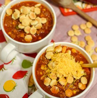 Two bowls of homemade no bean chili topped with oyster crackers and shredded cheese.