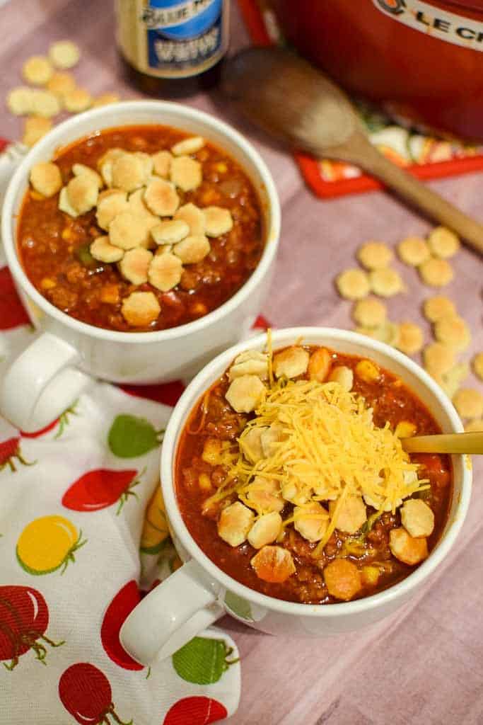 Two bowls of homemade no bean chili topped with oyster crackers and shredded cheese.