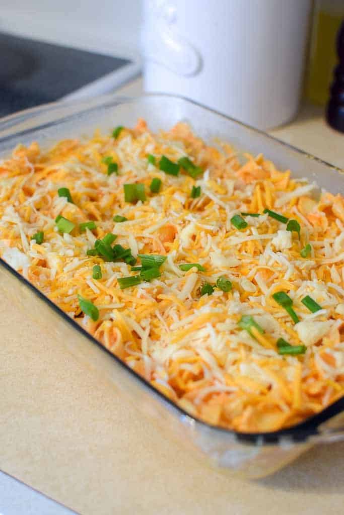 Midwest buffalo chicken casserole in a 9 by 13 glass baking dish sitting on a kitchen counter.