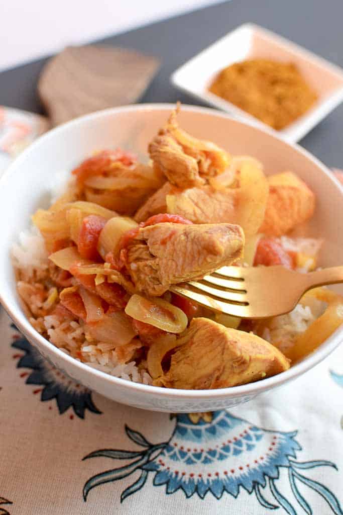 Bite of chicken curry on a fork.