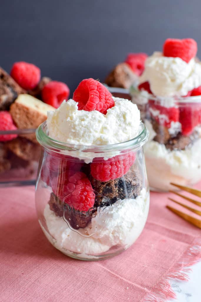 A brownie parfait with whipped cream and fresh raspberries.