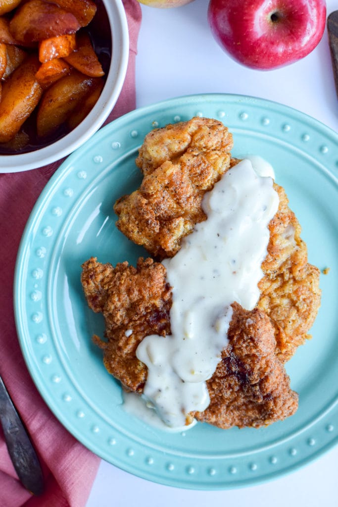 These perfect pan fried pork chops are topped with a easy to make homemade white gravy that's made with apples! This recipe will help you learn how to fry pork chops to perfection.
