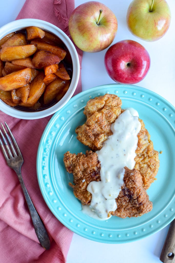 These perfect pan fried pork chops are topped with a easy to make homemade white gravy that's made with apples! This recipe will help you learn how to fry pork chops to perfection.