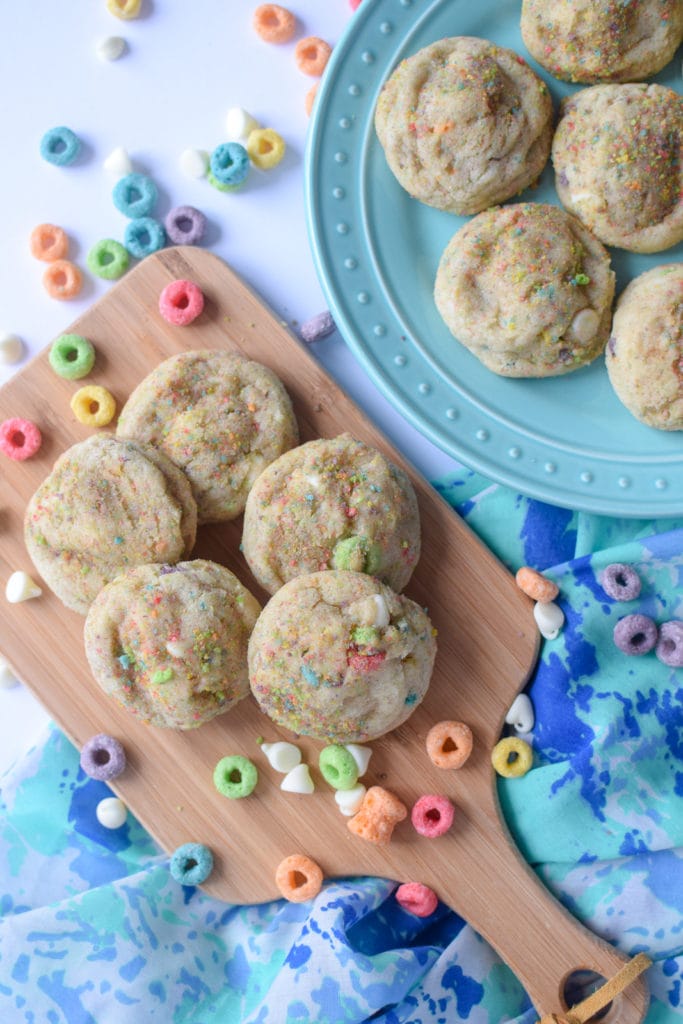 Froot loop sugar cookies on a blue plate and wooden serving tray.