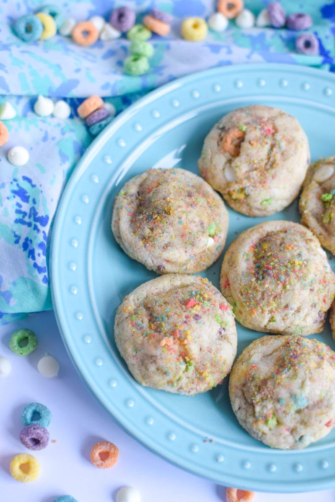 Soft sugar cookies on a blue plate surrounded by froot loops.