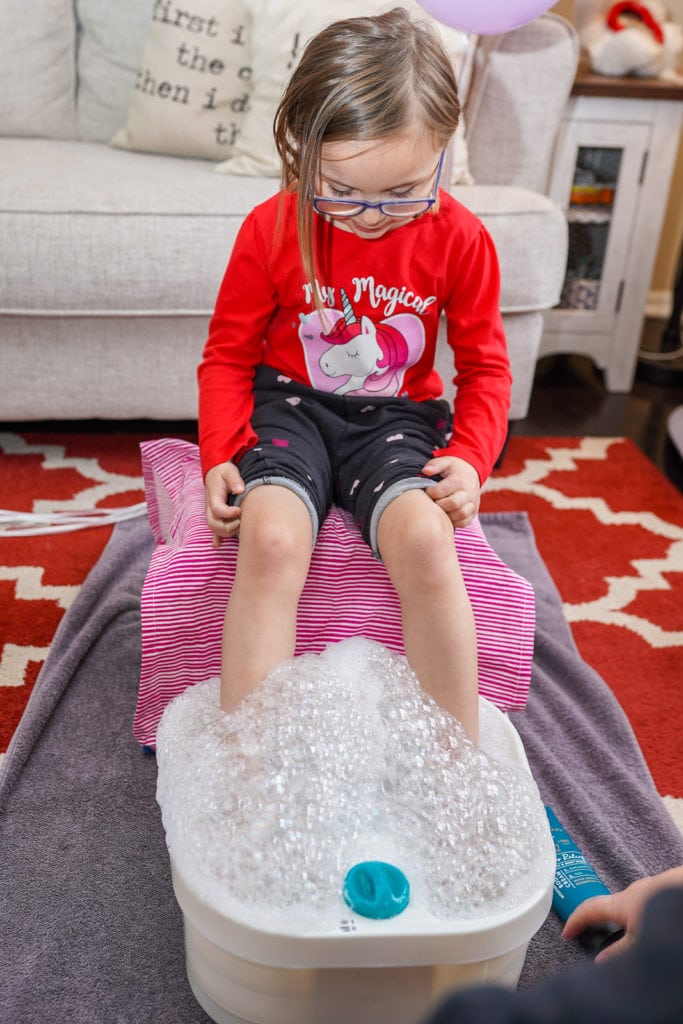 Child enjoying pedicure and foot spa at home.