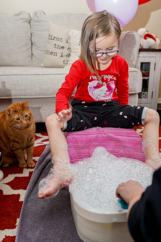 Child enjoying pedicure and foot spa at home.