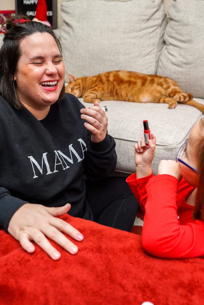Mother laughing after getting lipstick applied by daughter.