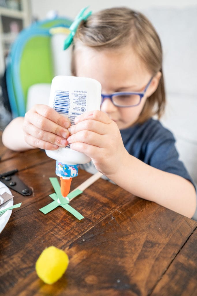 Child gluing items to plate while making craft.