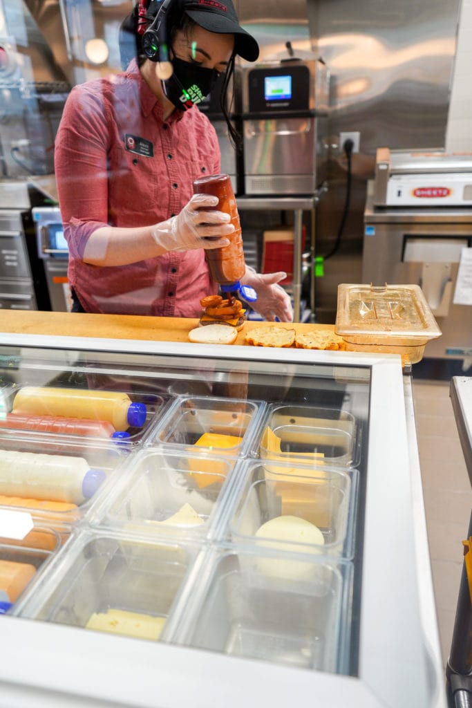 Employee topping burger at Sheetz.