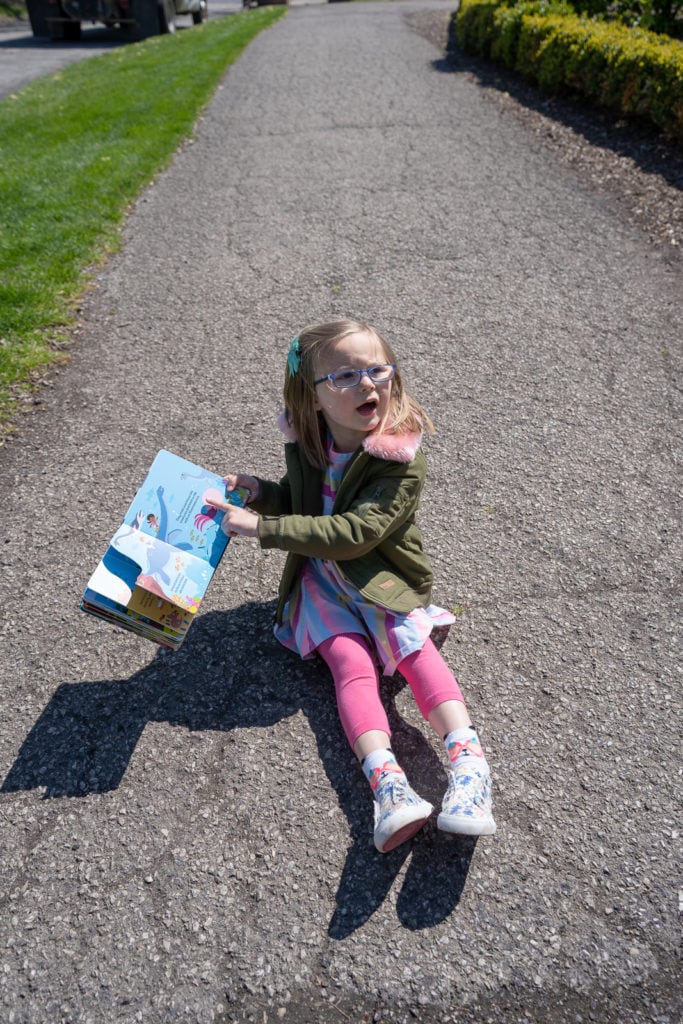 Child reading book outside the library.