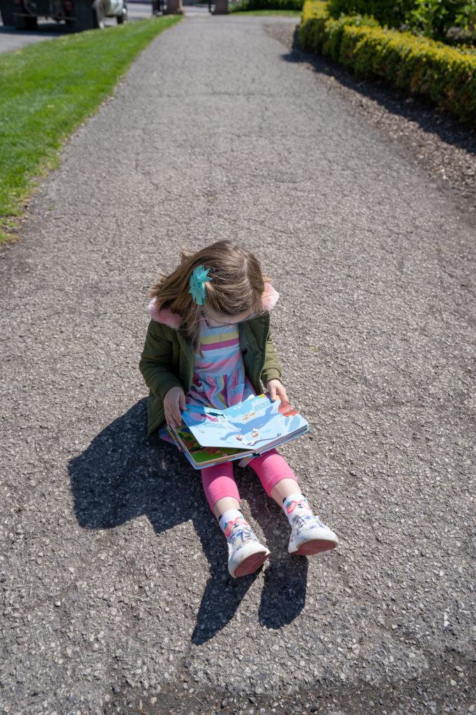 Child reading book in topiary garden.