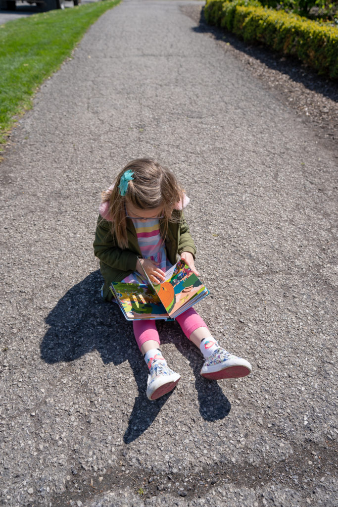 Child flipping through book outdoors.