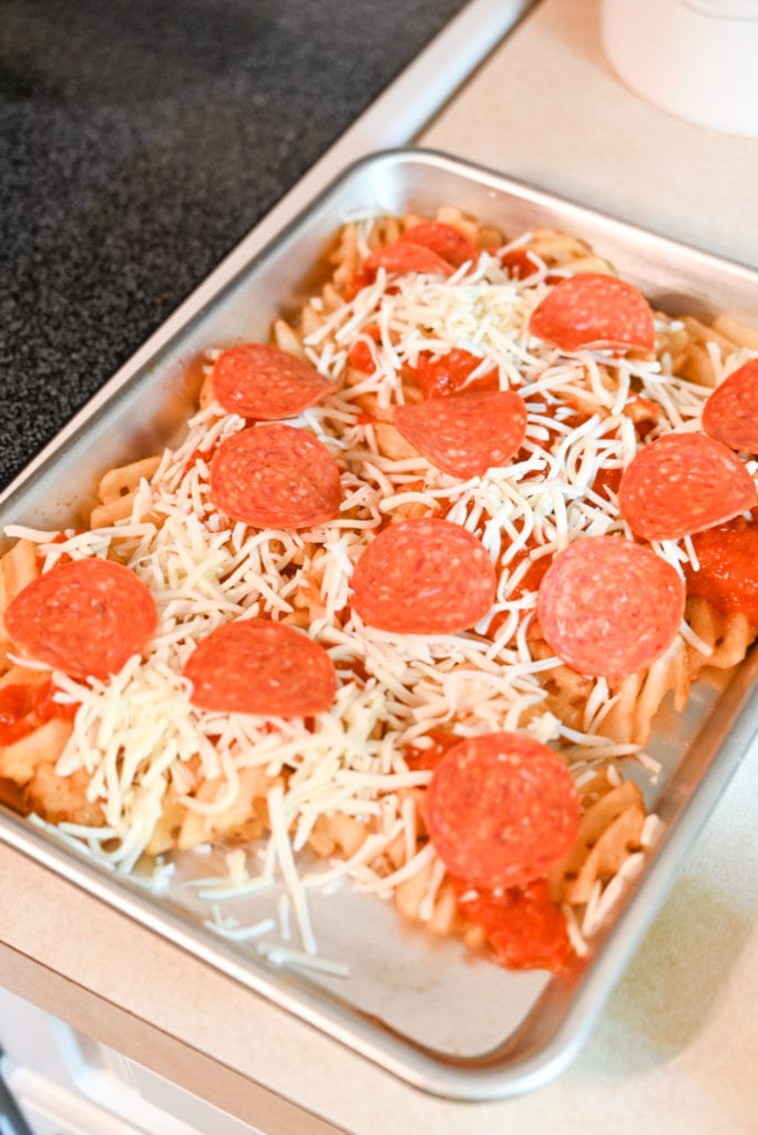 pizza fries get topped with shredded mozzarella cheese and sliced pepperoni.