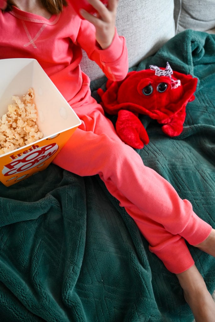 Child enjoying popcorn while wearing pact pajamas on the couch.