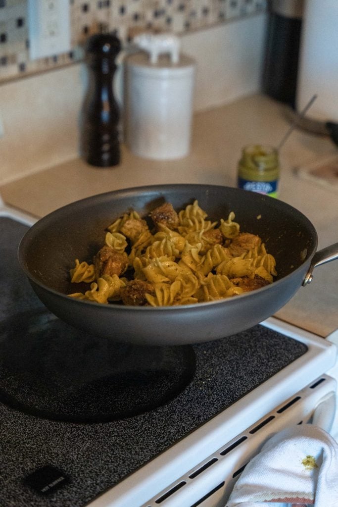 Tossing pasta in pan with Pesto Genovese For Pasta Dinner.