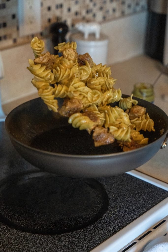 Tossing pasta in pan with Pesto Genovese For Pasta Dinner.