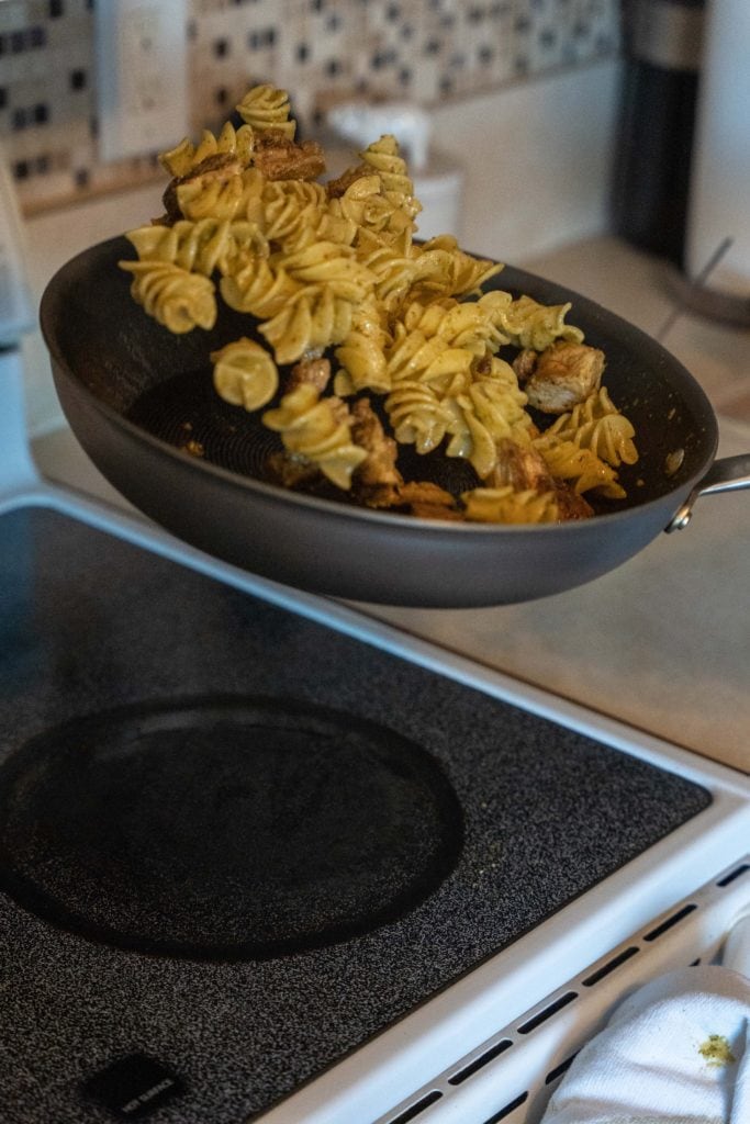 Tossing pasta in pan with Pesto Genovese For Pasta Dinner.