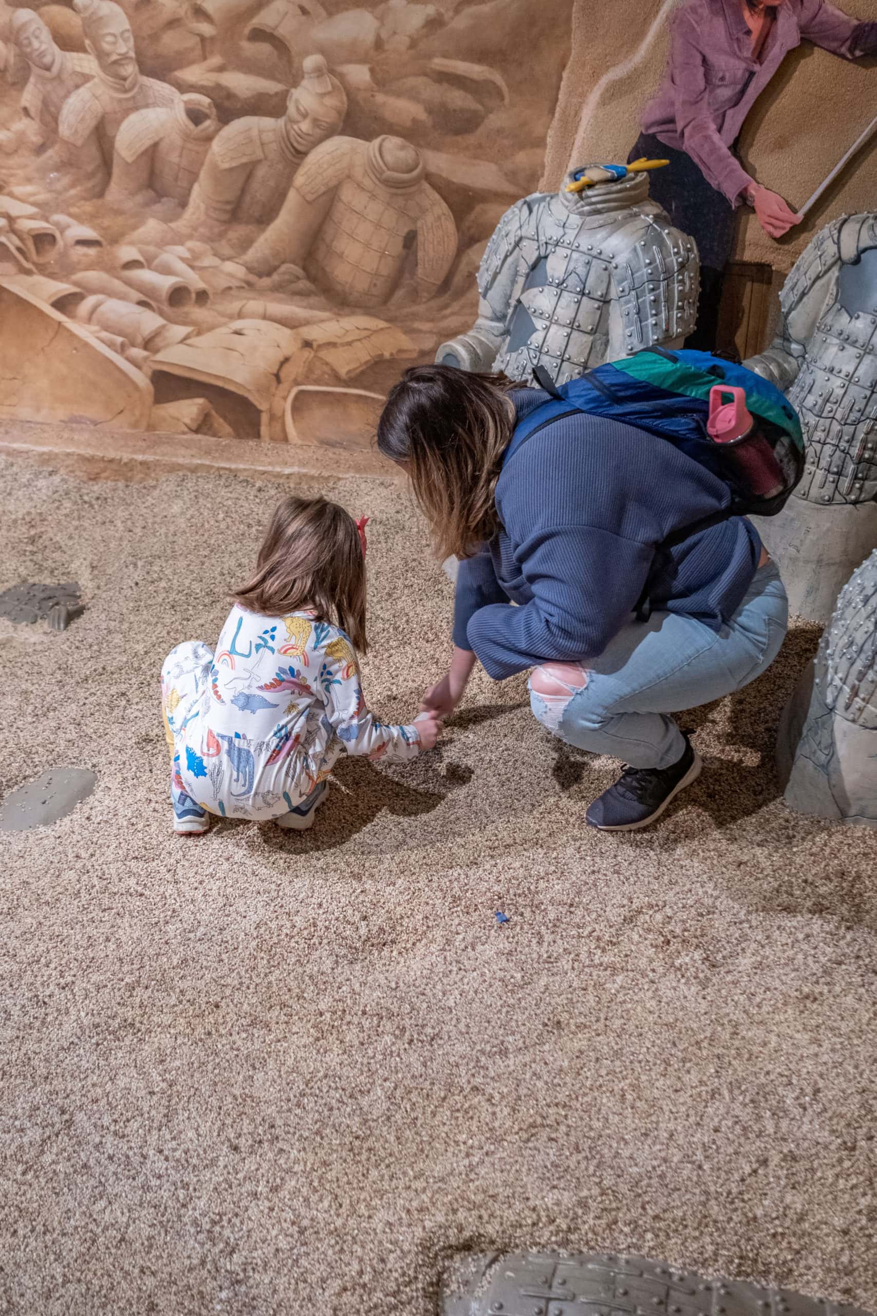 Family digging in an archaeology exhibit inside of the Children's Museum Of Indianapolis.