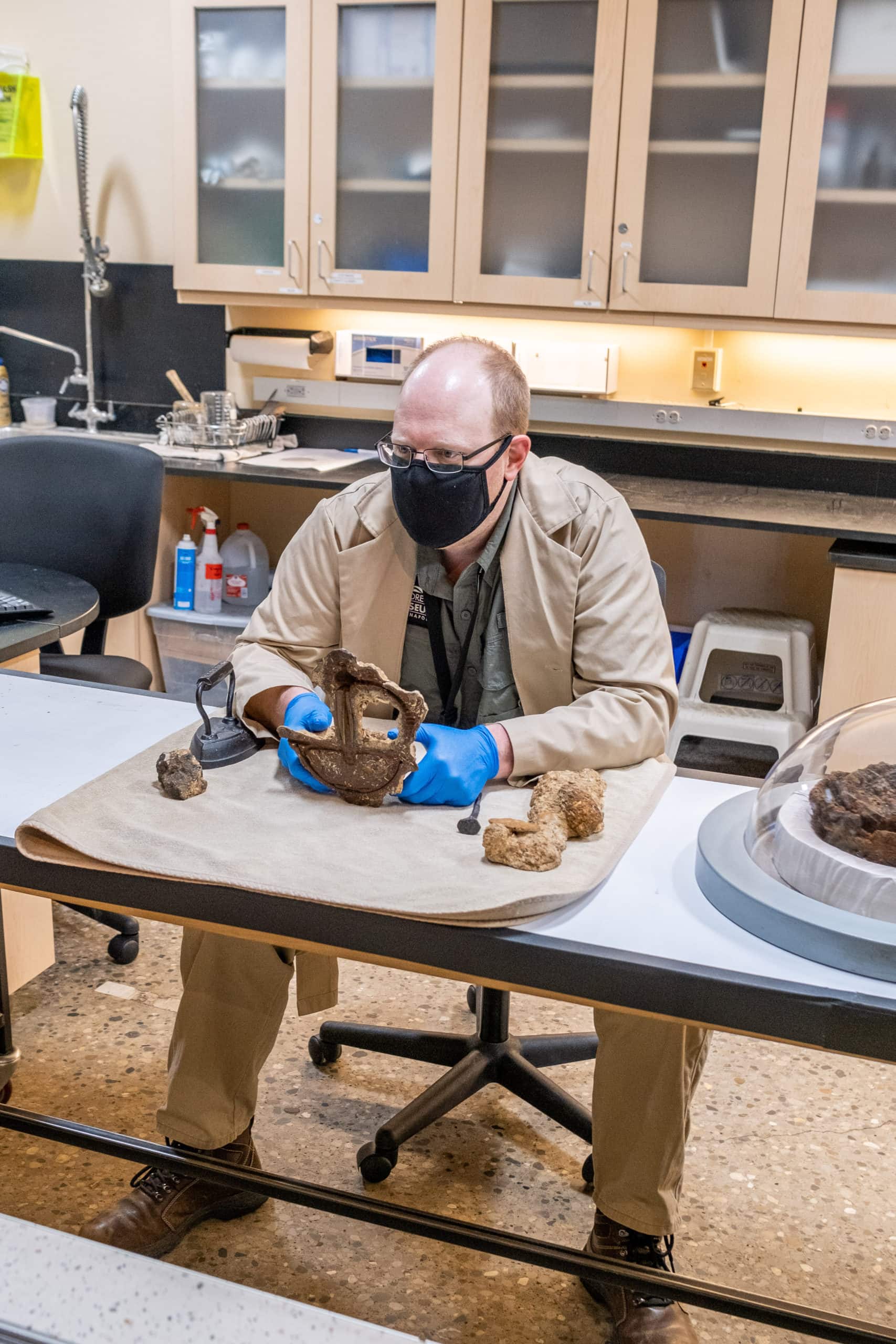 Team member showing fossils to families inside of the Children's Museum Of Indianapolis.