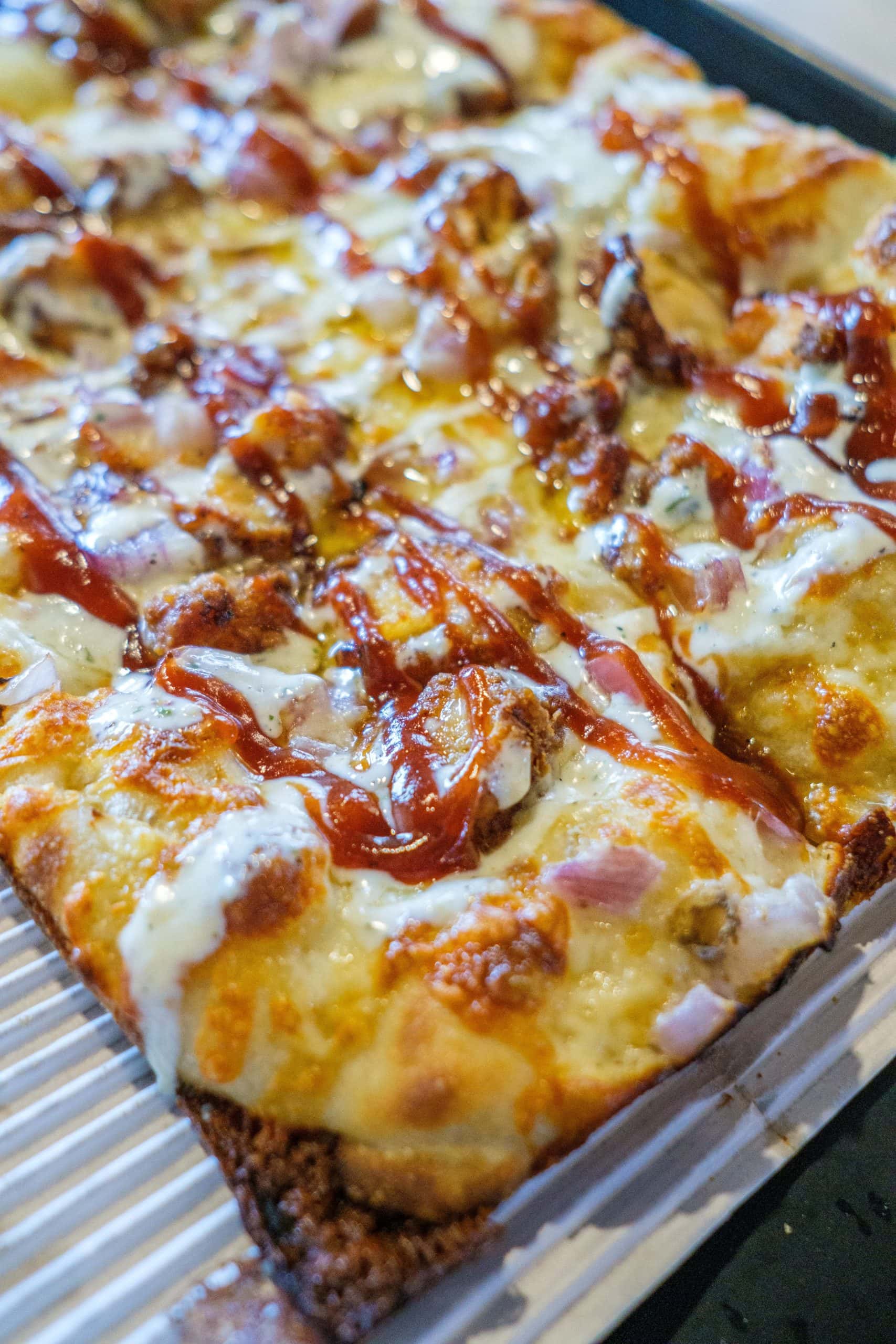 Bee Bee Q Detroit Style Pizza with garlic sauce, fried chicken, onion, hot honey, bbq sauce, and a ranch drizzle at Sexton's Pizza in Hilliard, Ohio.