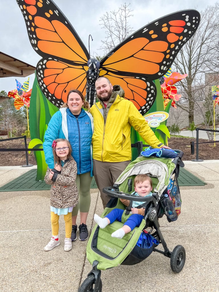 Family in front of butterfly stature inside the Indianapolis Zoo.