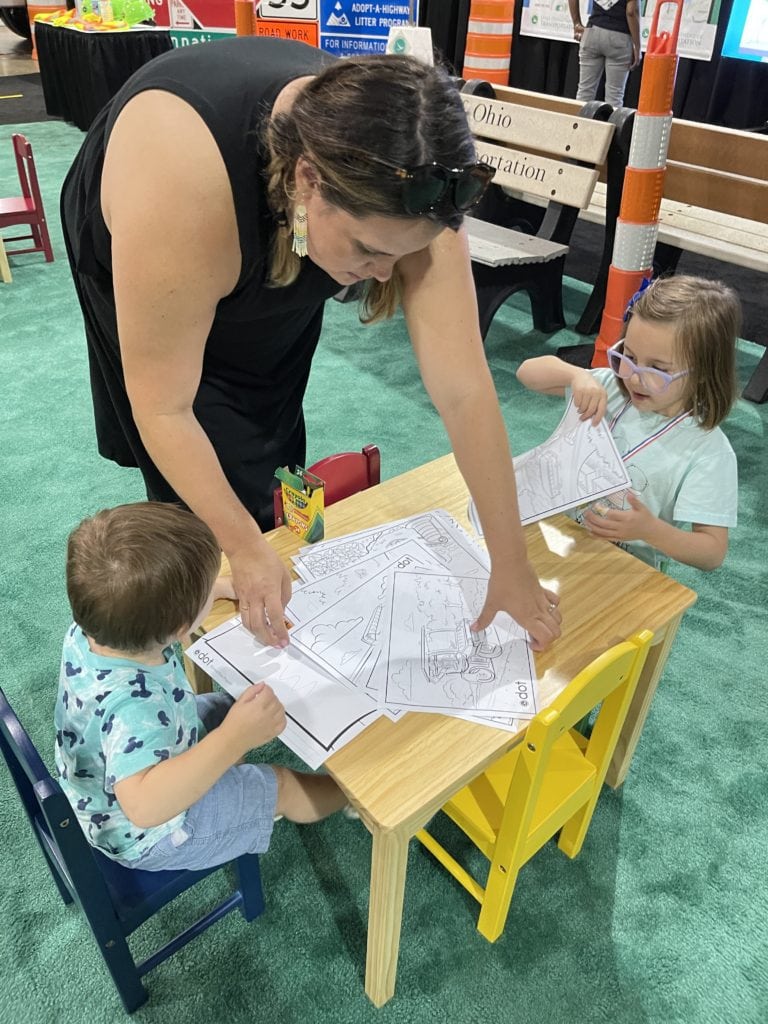 Mom and two kids coloring at The Ohio State Fair.