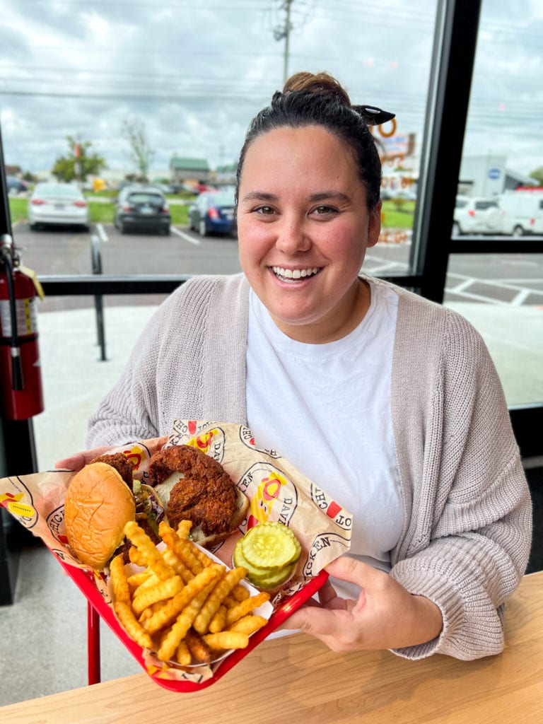 Woman holding Chicken slider and tender at Dave's Hot Chicken in Columbus, Ohio. 