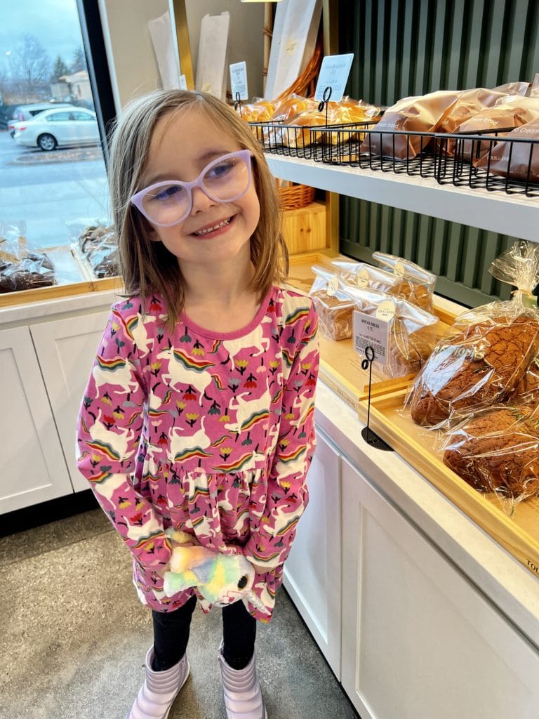 Young girl smiling while standing next to baked goods at TOUS les JOURS in Columbus Ohio.