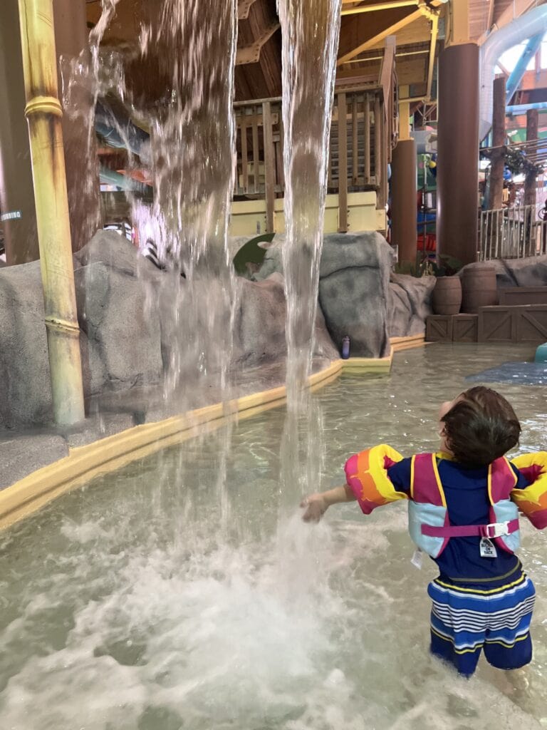 Little boy in a waterfall inside of a water park.